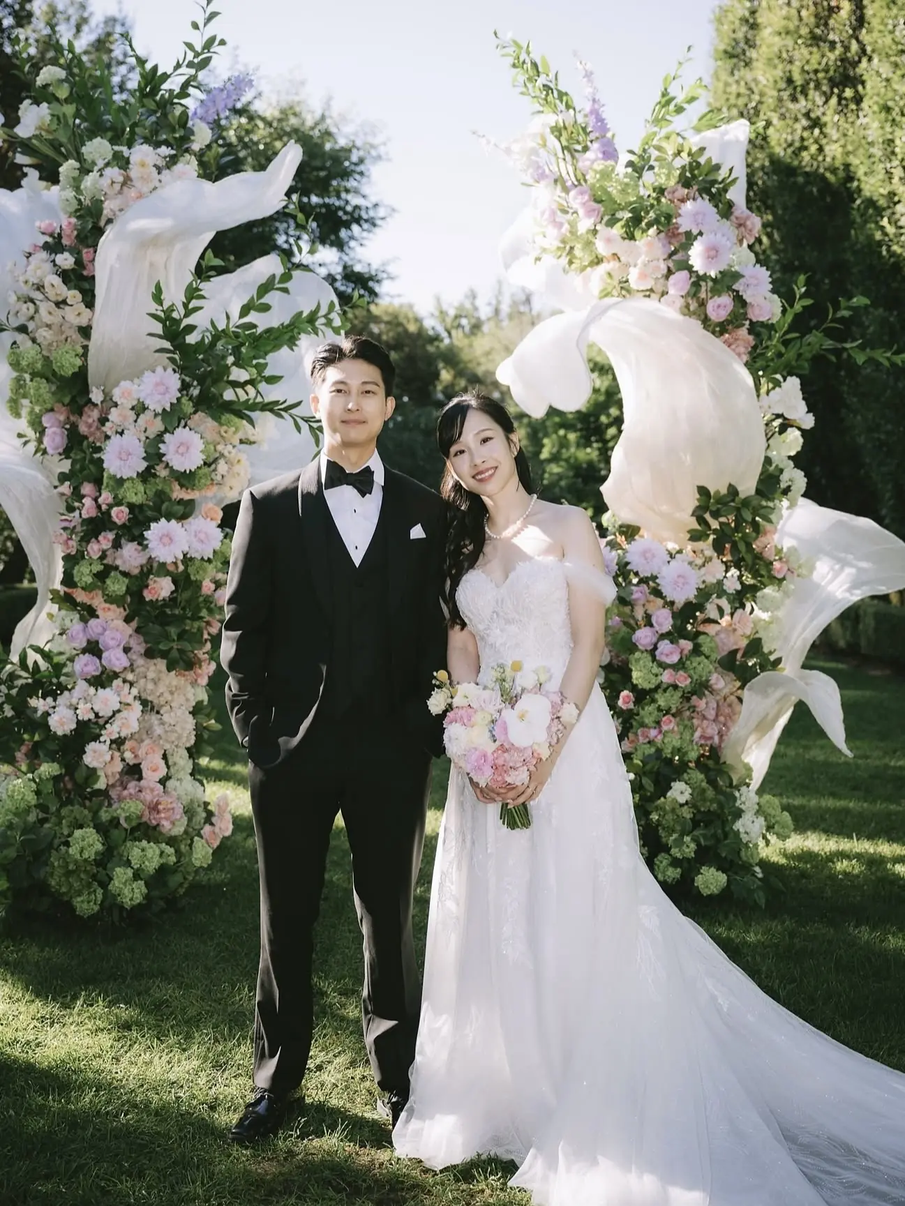 Newlyweds beneath a garden floral arch