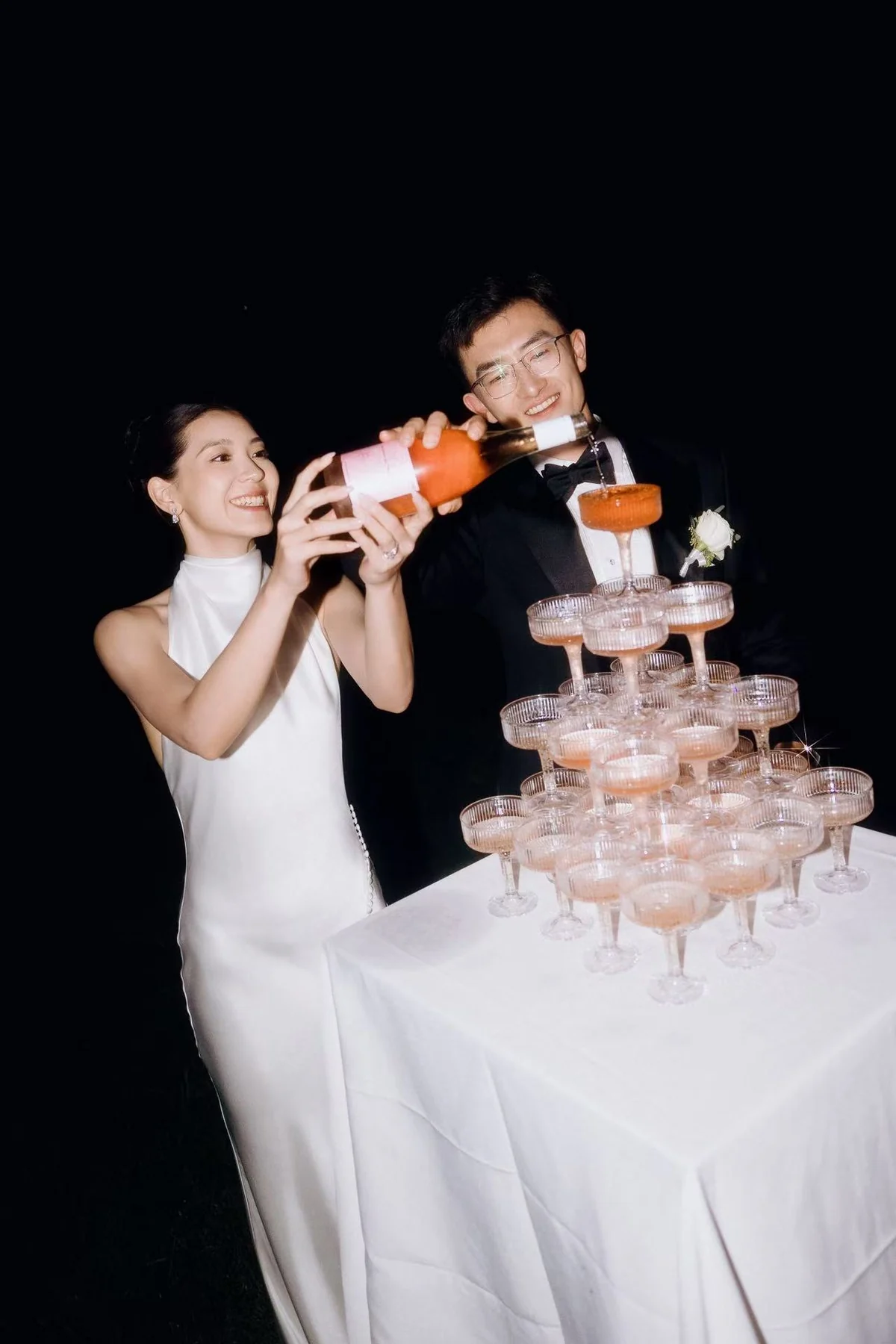 Newlyweds pouring a champagne tower at their reception