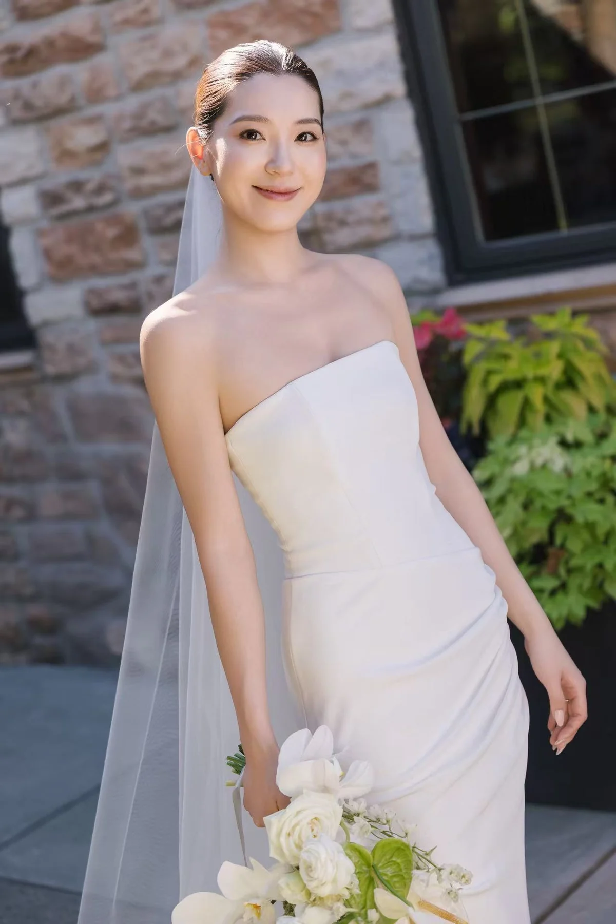 Bride with a white bouquet outside a stone building