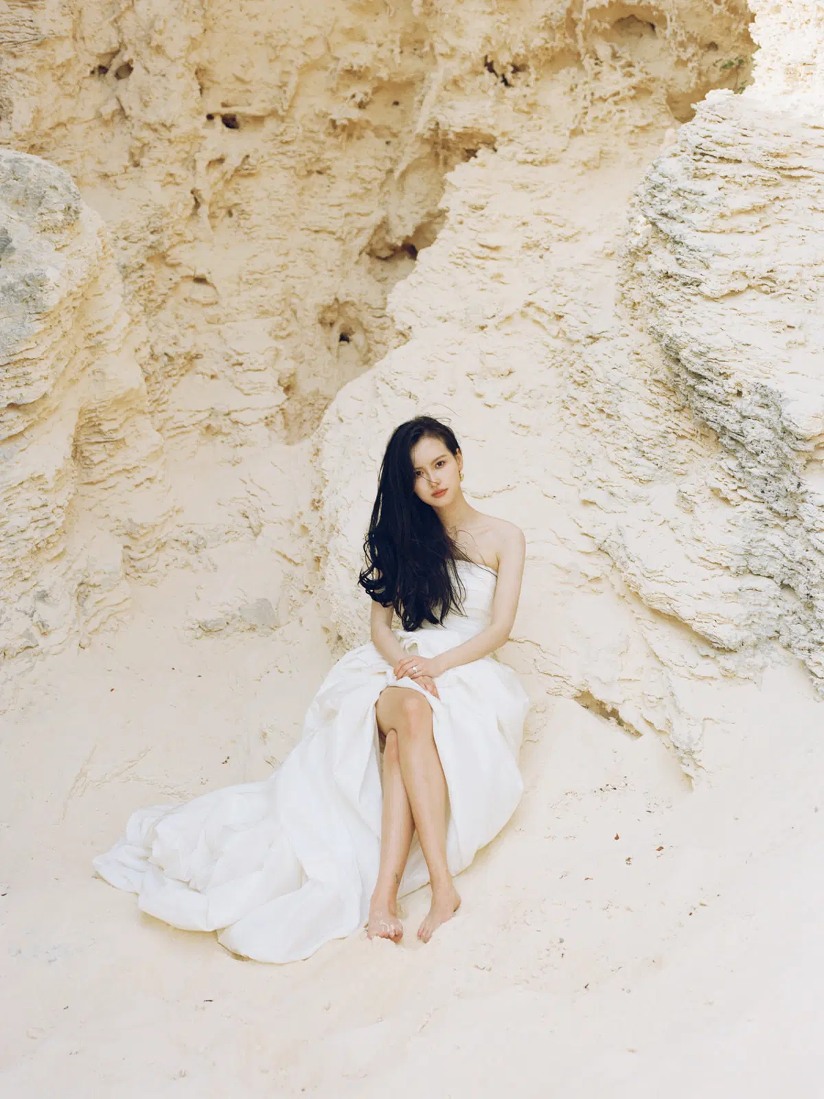 Seated bride against a sculptural stone wall