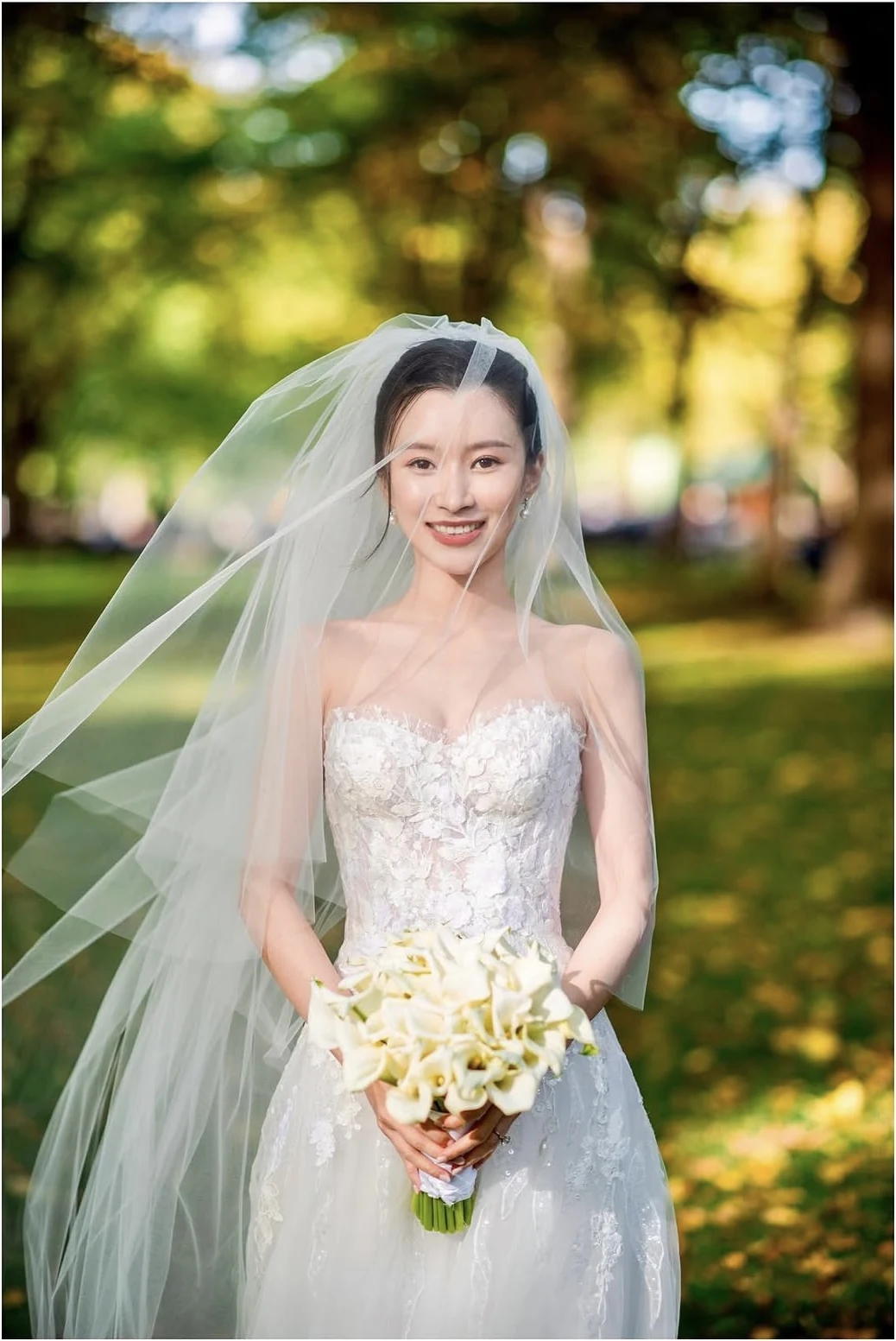Bride outdoors in a veil holding white calla lilies